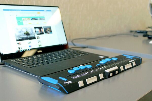 Ein Laptop auf einem Schreibtisch mit Braille-Assistenzsystem